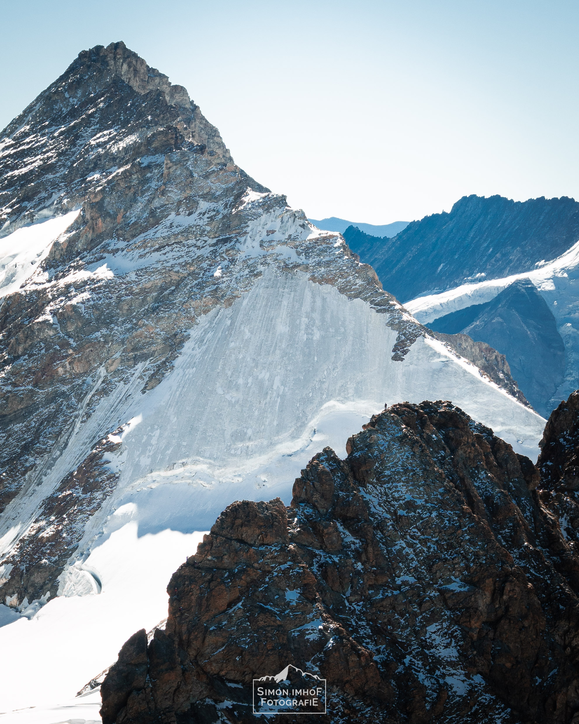 Mensch auf Eiger Südgrat mit Fiescherhorn im Hintergrund, Adventures with Fabi, der Bergführer, Aussicht, Fabian Bendlin, Blick zurück auf dem Mittellegigrat, Überschreitung, Eiger Integral, Grat, Gratklettern, Bern, Simon Imhof, Alpen, Bergtour, Berner Oberland, Eiger, Gipfel, Gleitschirm, Hike and Fly, Hütte, Landschaftsfotografie, Mittellegigrat, Outdoor, Outdoorfotografie, SAC, Schweiz, Seilschaft, Simon Imhof, Sommer, Sonnenaufgang, Sony, Sportfotografie