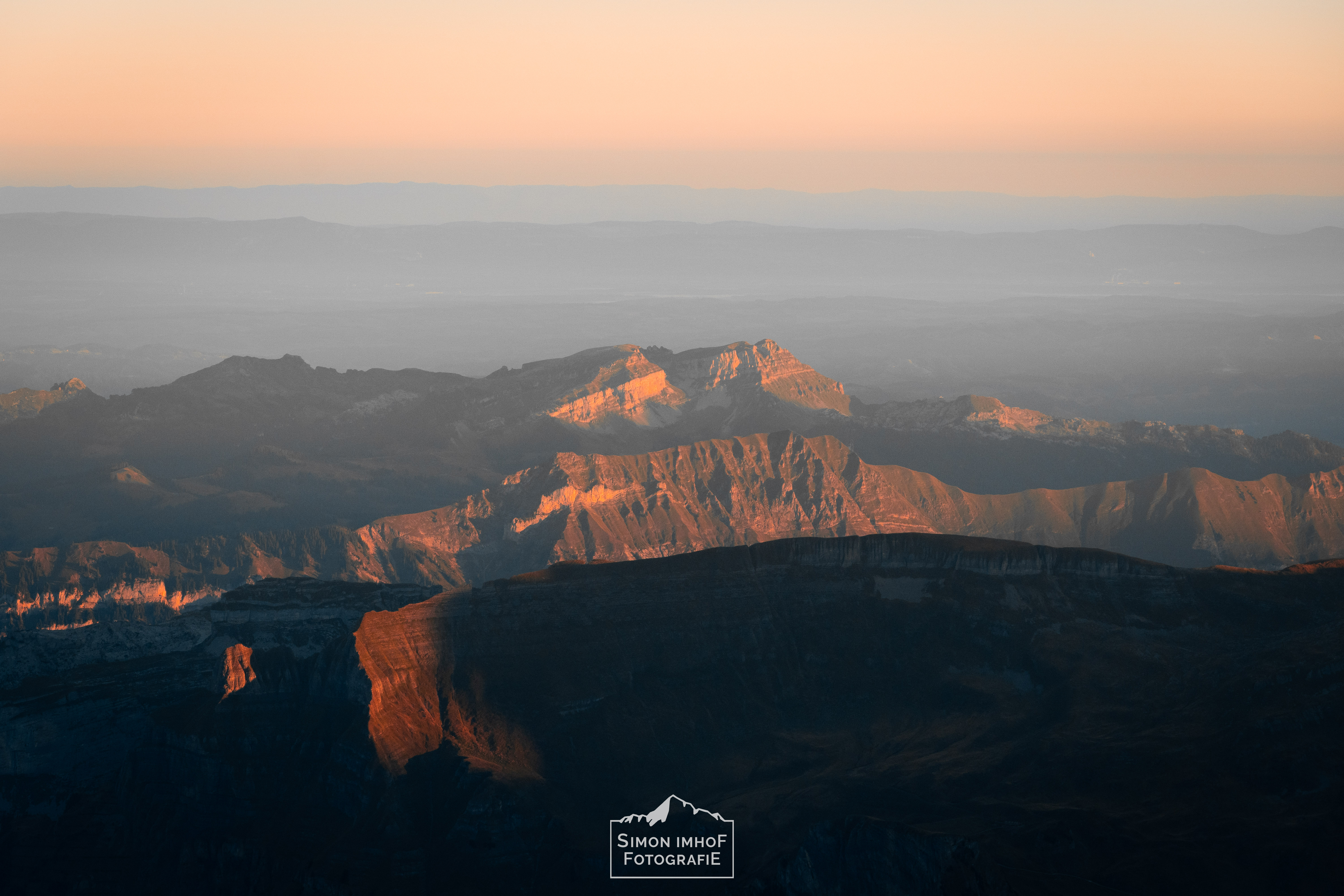 Landschaftsbild mit Bergen im Vordergrund und das Mittelland im Hintergrund. Morgenstimmung.Seilhandling, Friends, Karabiner, Mensch auf Eiger Südgrat mit Fiescherhorn im Hintergrund, Adventures with Fabi, der Bergführer, Aussicht, Fabian Bendlin, Blick zurück auf dem Mittellegigrat, Überschreitung, Eiger Integral, Grat, Gratklettern, Bern, Simon Imhof, Alpen, Bergtour, Berner Oberland, Eiger, Gipfel, Gleitschirm, Hike and Fly, Hütte, Landschaftsfotografie, Mittellegigrat, Outdoor, Outdoorfotografie, SAC, Schweiz, Seilschaft, Simon Imhof, Sommer, Sonnenaufgang, Sony, Sportfotografie